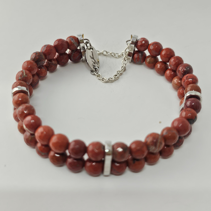 A handcrafted double-strand bracelet featuring 4mm faceted Red Jasper beads in warm earthy tones. The design is accented with silver-tone spacers, a matching clasp, and a delicate silver chain with an engraved tag.