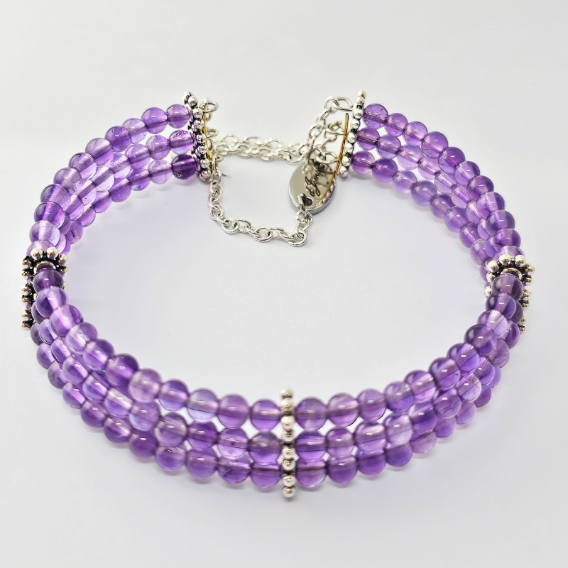 Amethyst 4mm Triple Strand Bracelet featuring rich purple beads on silver-plated memory wire with a fixed safety chain.