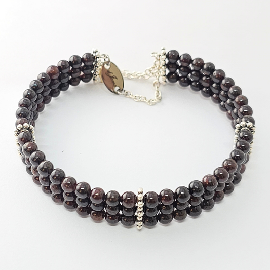 Garnet 4mm Triple Strand Bracelet featuring deep red beads on silver-plated memory wire with a fixed safety chain.