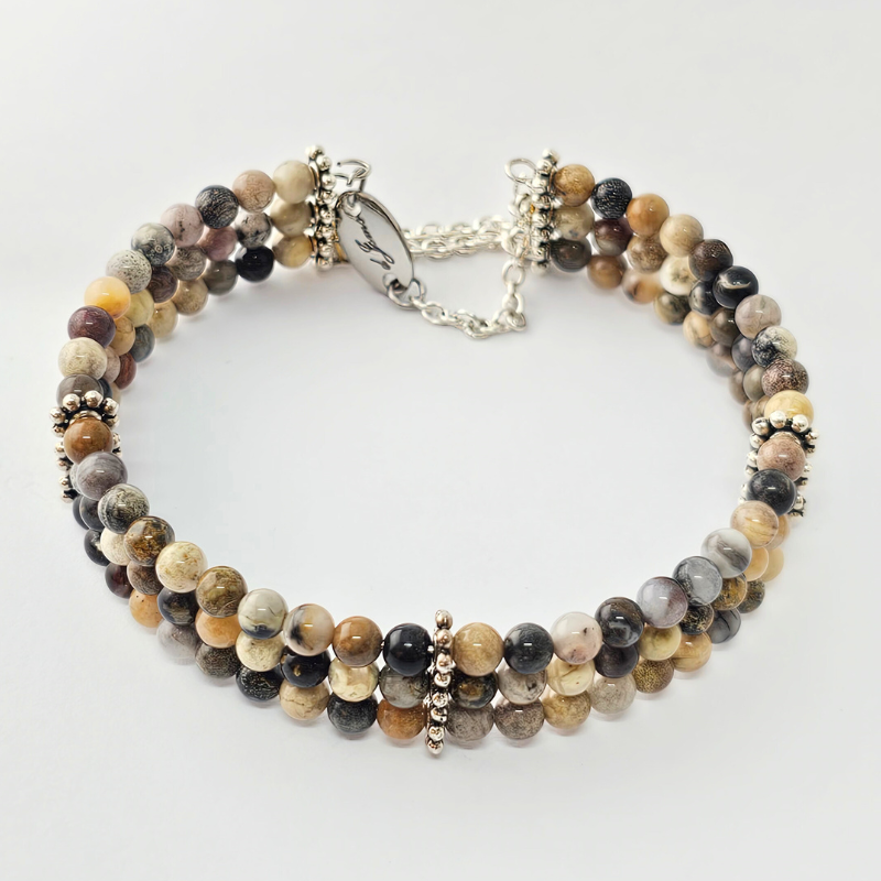 Triple strand bracelet made of 6mm polished multi-colored picture jasper beads, accented with silver-toned decorative spacers and a chain clasp engraved with “Je’Luna.”