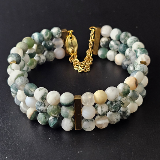 Matte Tree Agate 6mm triple strand bracelet featuring soft green and white natural stone beads, accented with gold-tone spacers and clasp, displayed on a black background.