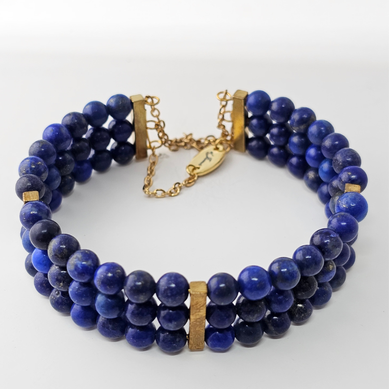Triple strand bracelet featuring 6mm deep blue Lapis Lazuli beads with gold-toned rectangular spacers and a matching gold chain clasp engraved with “Je’Luna.”