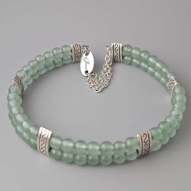 Double strand bracelet made of 4mm green aventurine beads, accented with silver-toned spacers and a delicate silver chain clasp featuring an engraved tag.