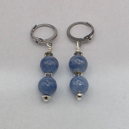 Pair of earrings with blue beads and silver loops on a light gray background