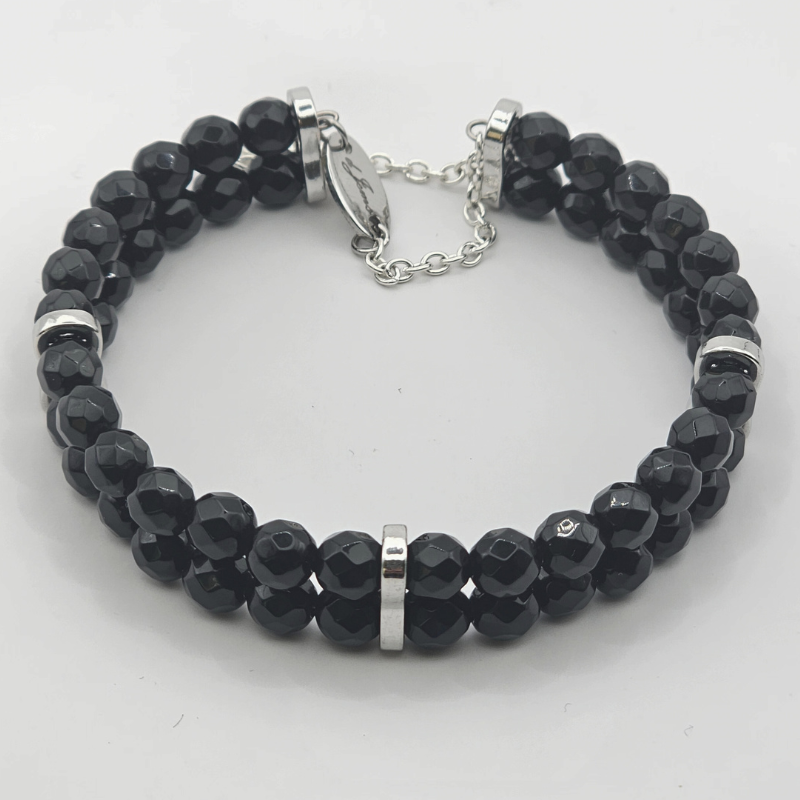 Double strand faceted black onyx bracelet with silver spacers and a silver chain clasp, displayed on a white background.