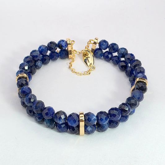 Blue beaded bracelet with gold accents on a white background
