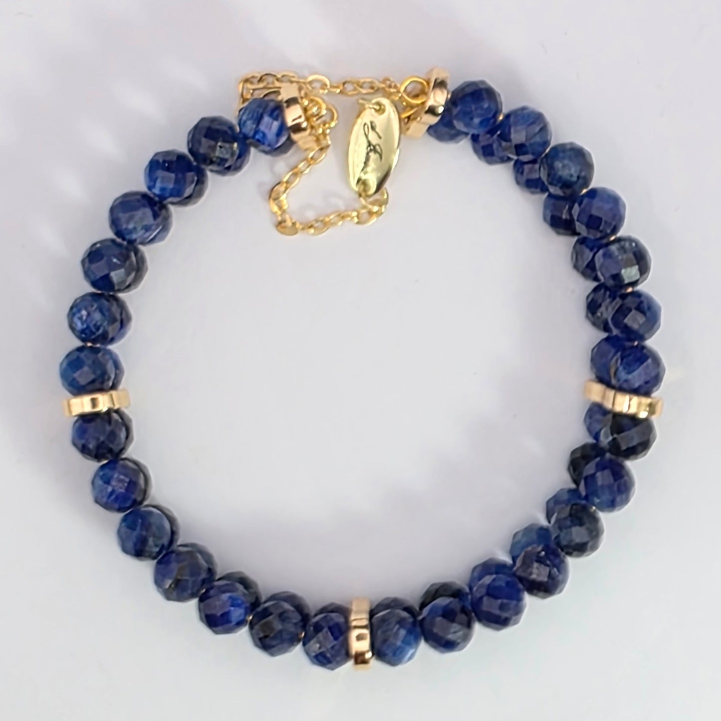 Blue beaded bracelet with gold accents on a light gray background