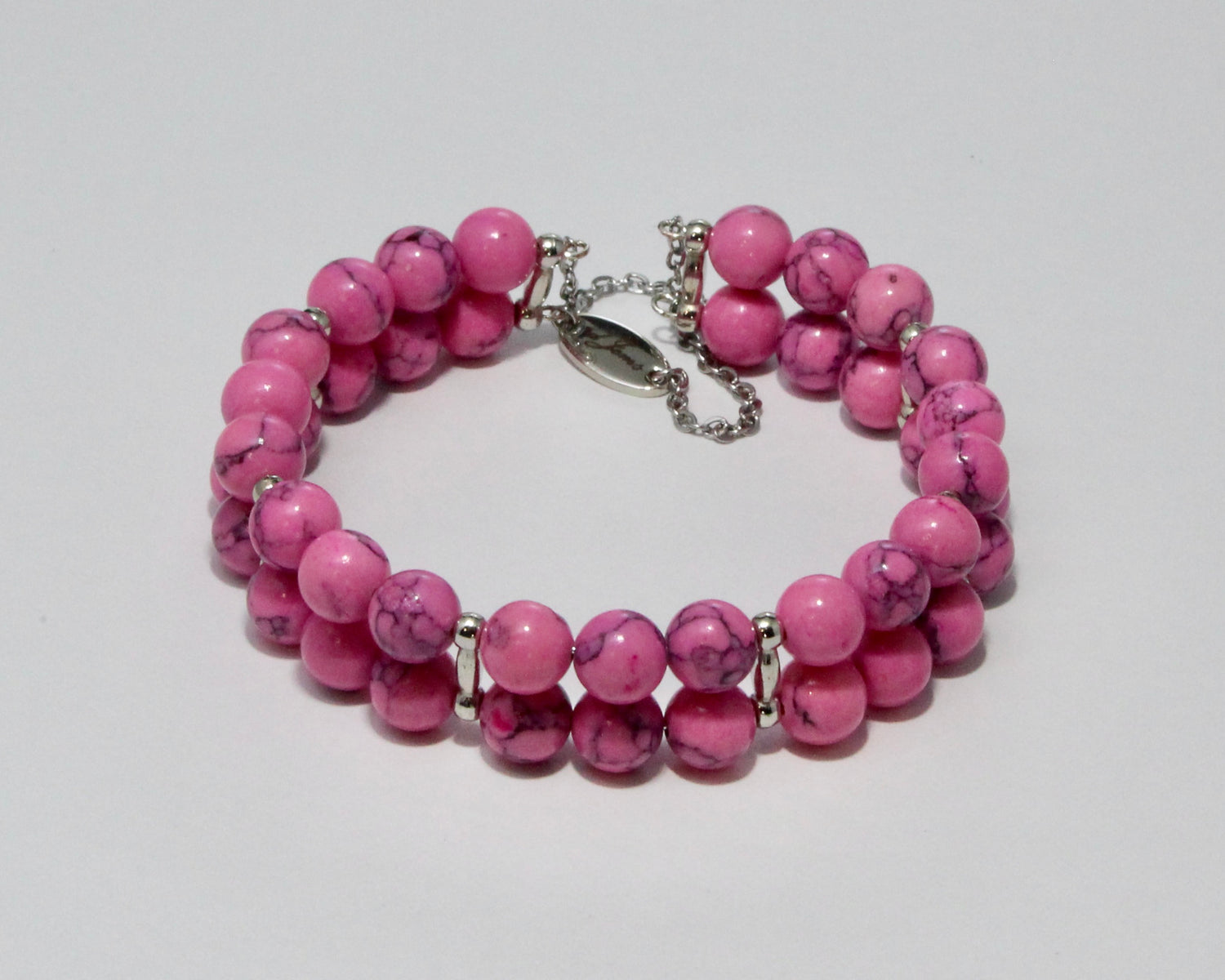 Handmade Pink Howlite Bracelet showcasing 10mm soft pink beads on plated stainless steel memory wire with a fixed safety chain.