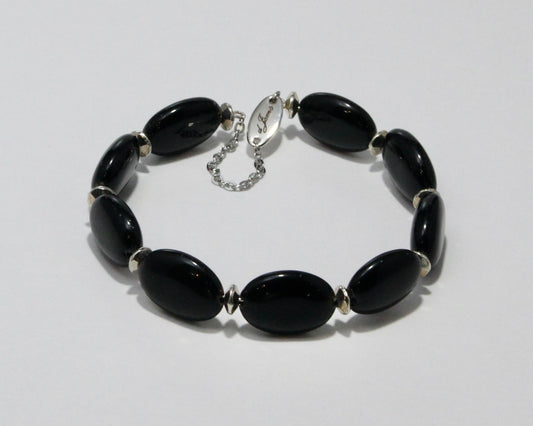 Handmade Black Onyx Bracelet showcasing 18x13mm glossy black beads with elegant spacers on plated stainless steel memory wire with a fixed safety chain.