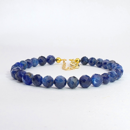 Blue beaded bracelet with a gold clasp on a white background