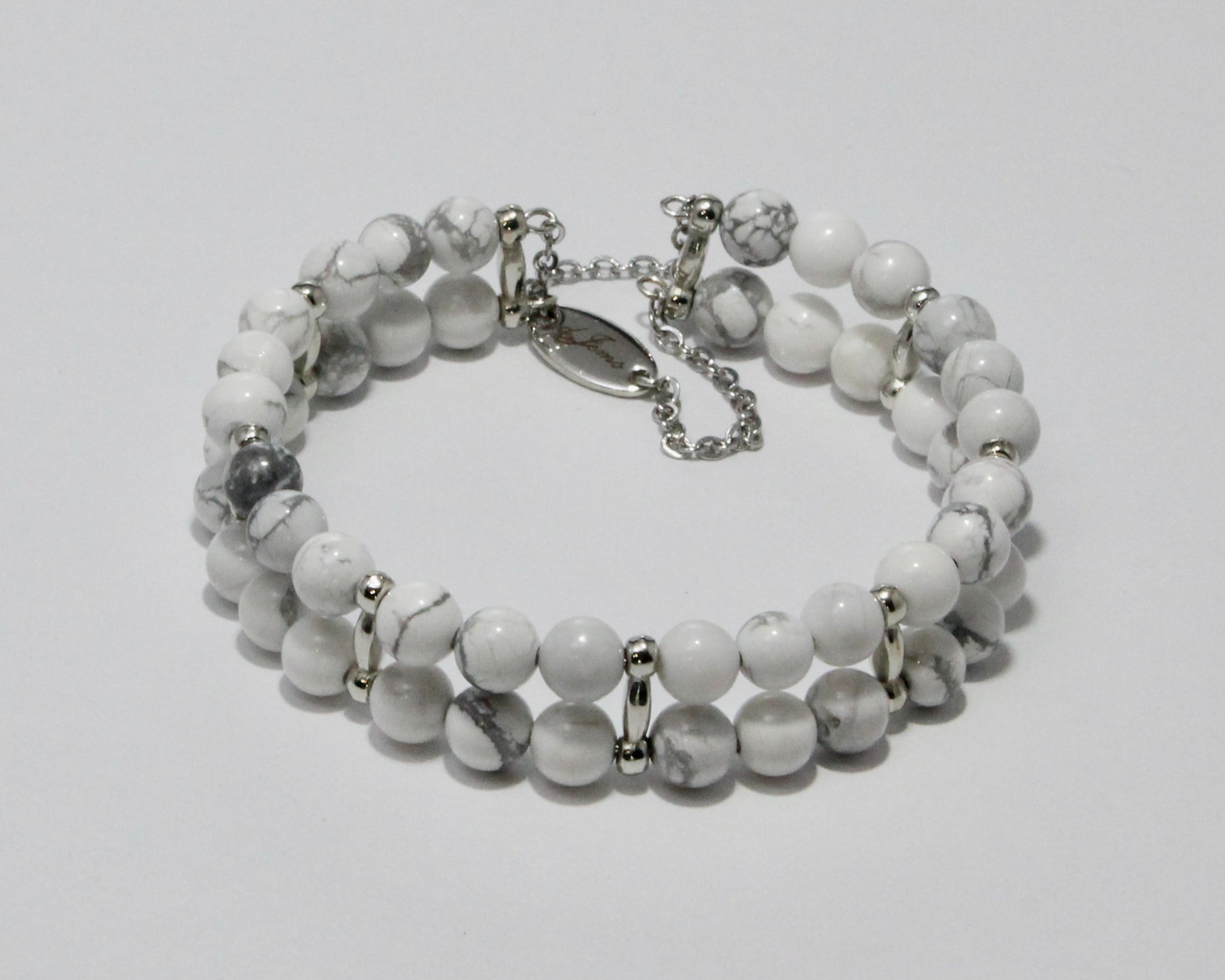 Handmade Howlite Bracelet showcasing 10mm white beads with soft gray veining on plated stainless steel memory wire with a fixed safety chain.

