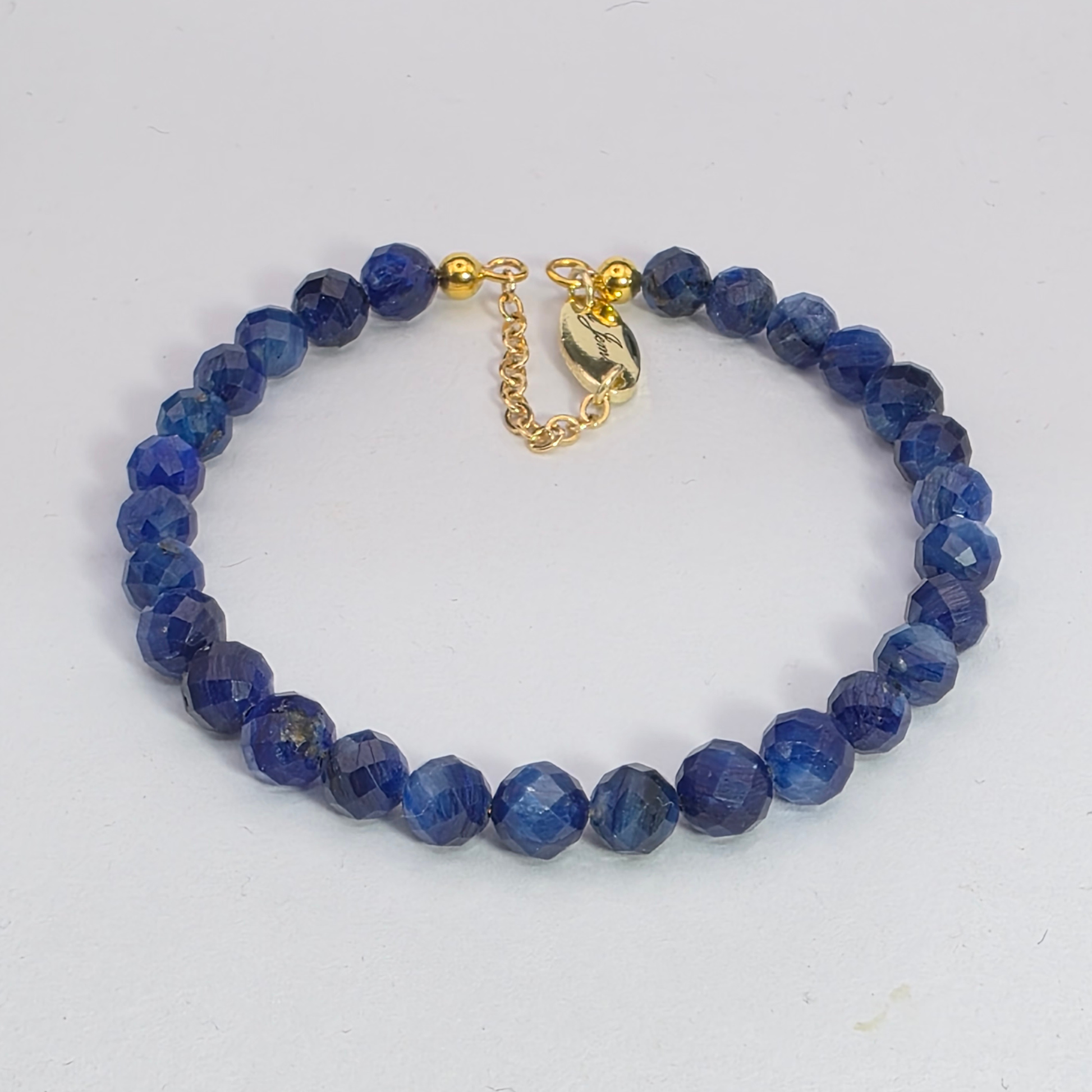 Blue beaded bracelet with a gold clasp on a white background