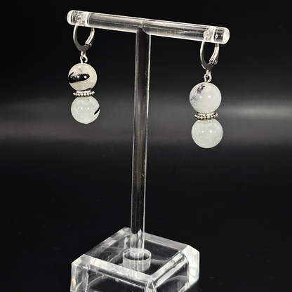 Pair of earrings on a clear stand against a black background- Tourmalated Quartz Drop Earrings