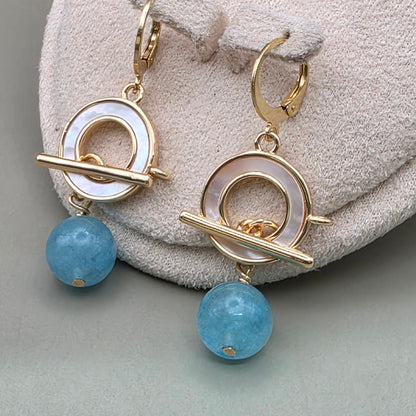 Aquamarine gold earrings on a textured surface