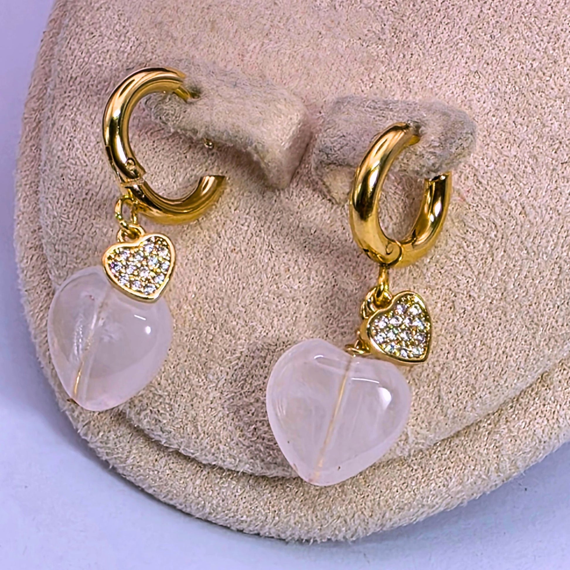 Close-up of a handcrafted Rose Quartz earringd accented with sparkling Cubic Zirconia gemstones. The jewelry is displayed on a soft beige background highlighting the natural pink hues of the quartz and the brilliant diamond-like shine of the CZ crystals for Valentine's Day.
