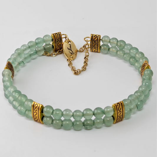 Double strand green aventurine bracelet with ornate gold spacers and a gold chain clasp, displayed on a white background.