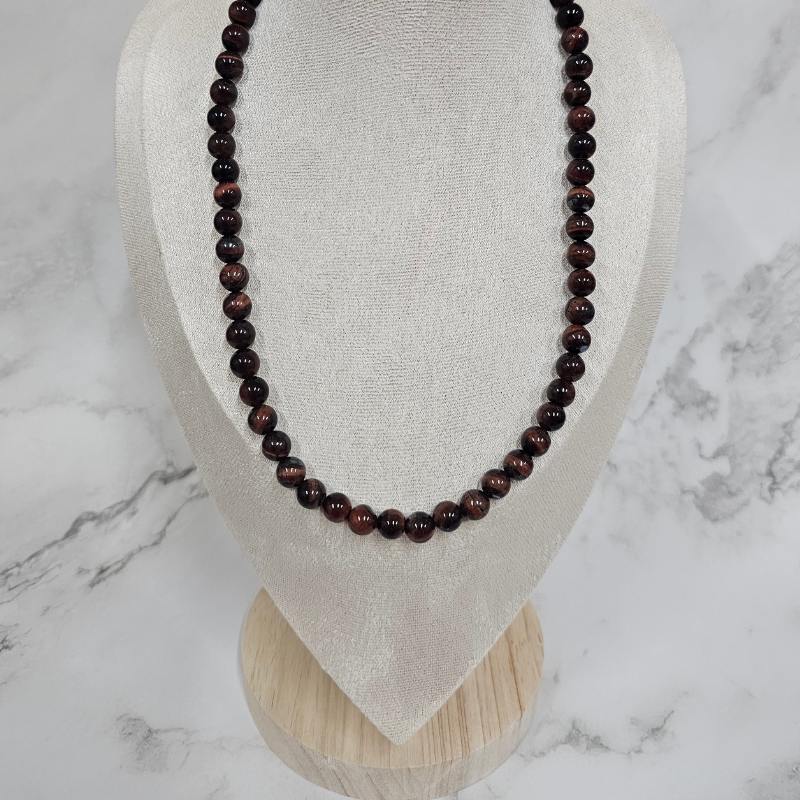 Beaded necklace on a mannequin bust against a marble background