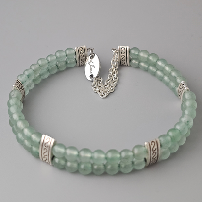 Double strand bracelet made of 4mm green aventurine beads, accented with silver-toned spacers and a delicate silver chain clasp featuring an engraved tag.