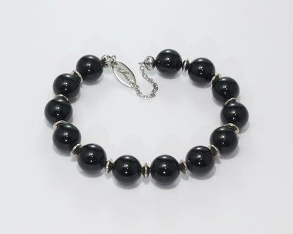 Handmade Black Tourmaline Bracelet showcasing 10mm deep black tourmaline beads with elegant spacers on plated stainless steel memory wire with a fixed safety chain.