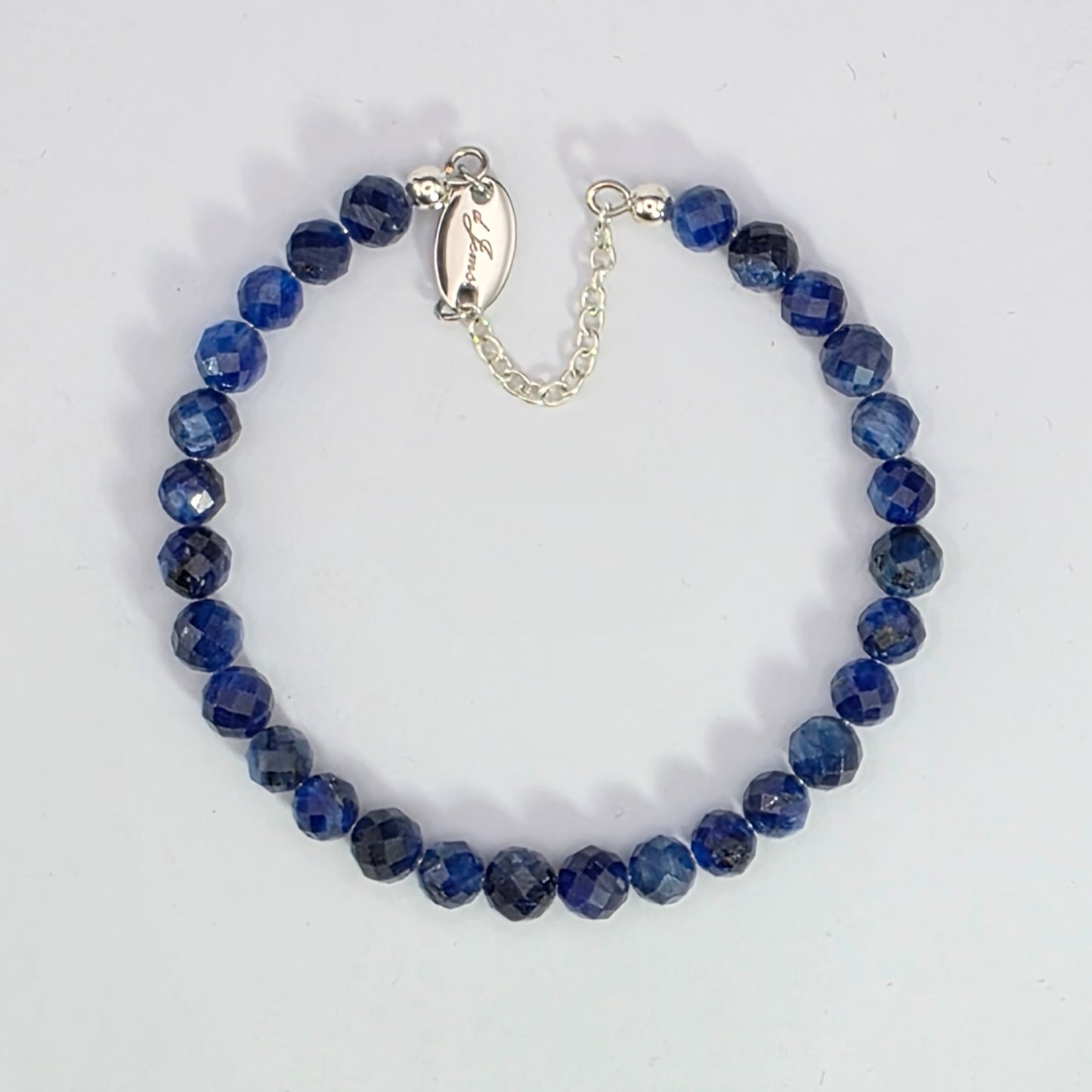 Blue beaded bracelet with silver clasp on a white background