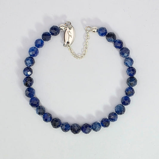 Blue beaded bracelet with silver clasp on a white background