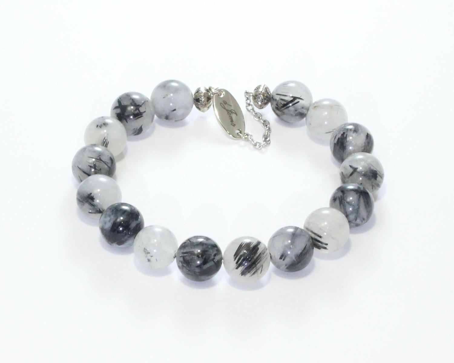Handmade Tourmalated Quartz Bracelet showcasing 10mm or 12mm beads blending clear quartz and black tourmaline on plated stainless steel memory wire with a fixed safety chain.

