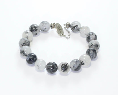 Handmade Tourmalated Quartz Bracelet showcasing 10mm or 12mm beads blending clear quartz and black tourmaline on plated stainless steel memory wire with a fixed safety chain.

