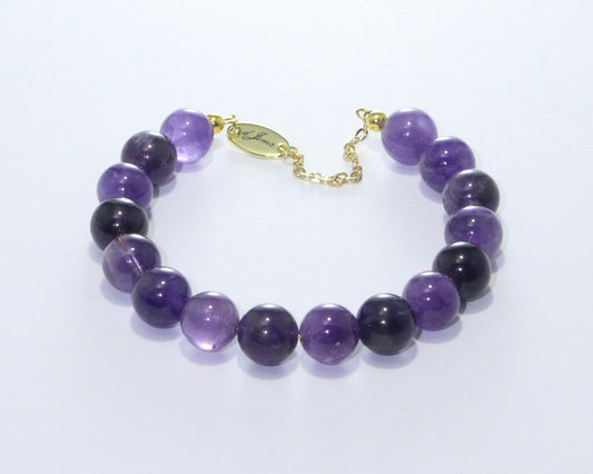 Handmade Amethyst Bracelet showcasing 10mm violet quartz beads on plated stainless steel memory wire with a fixed safety chain.
