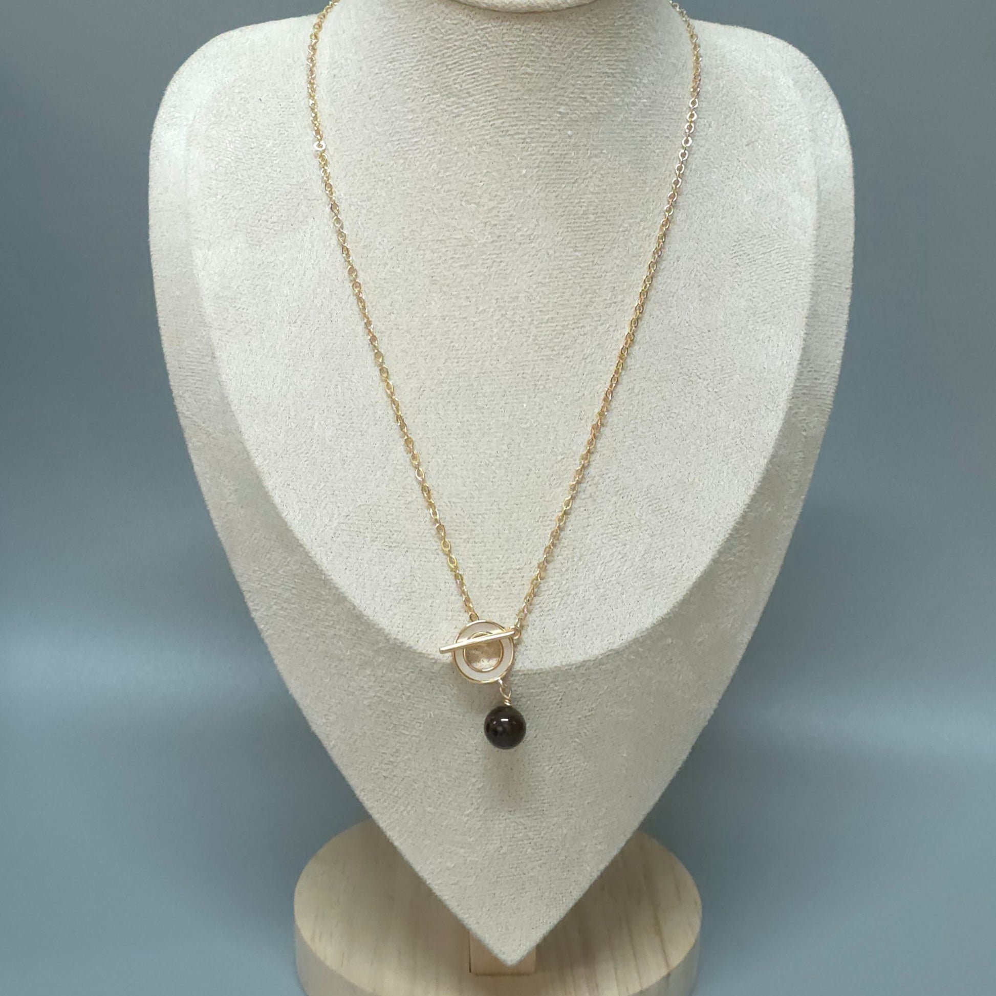 Garnet gold necklace with a pendant on a mannequin bust against a gray background