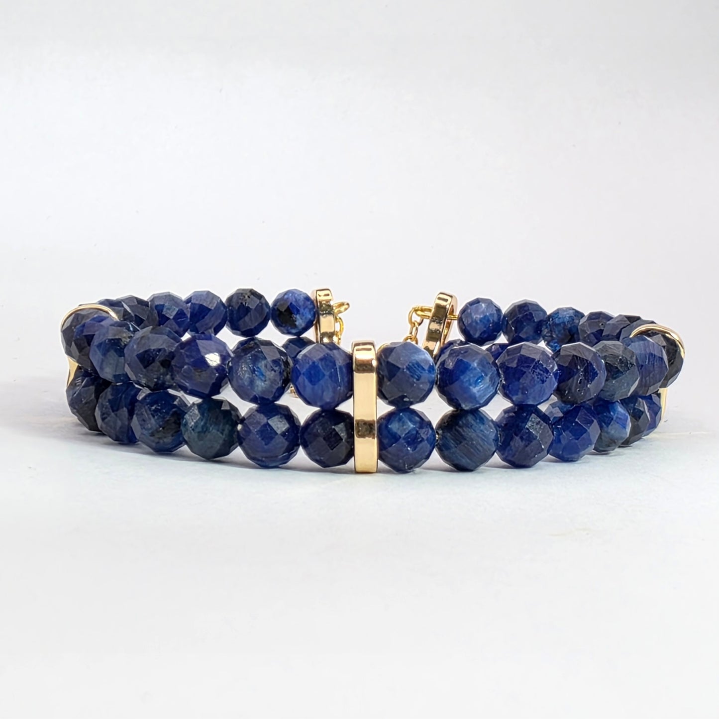 Blue beaded bracelet with gold accents on a white background