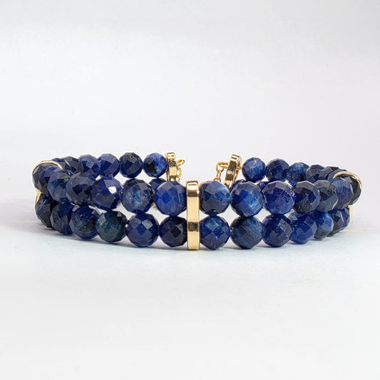 Blue beaded bracelet with gold accents on a white background