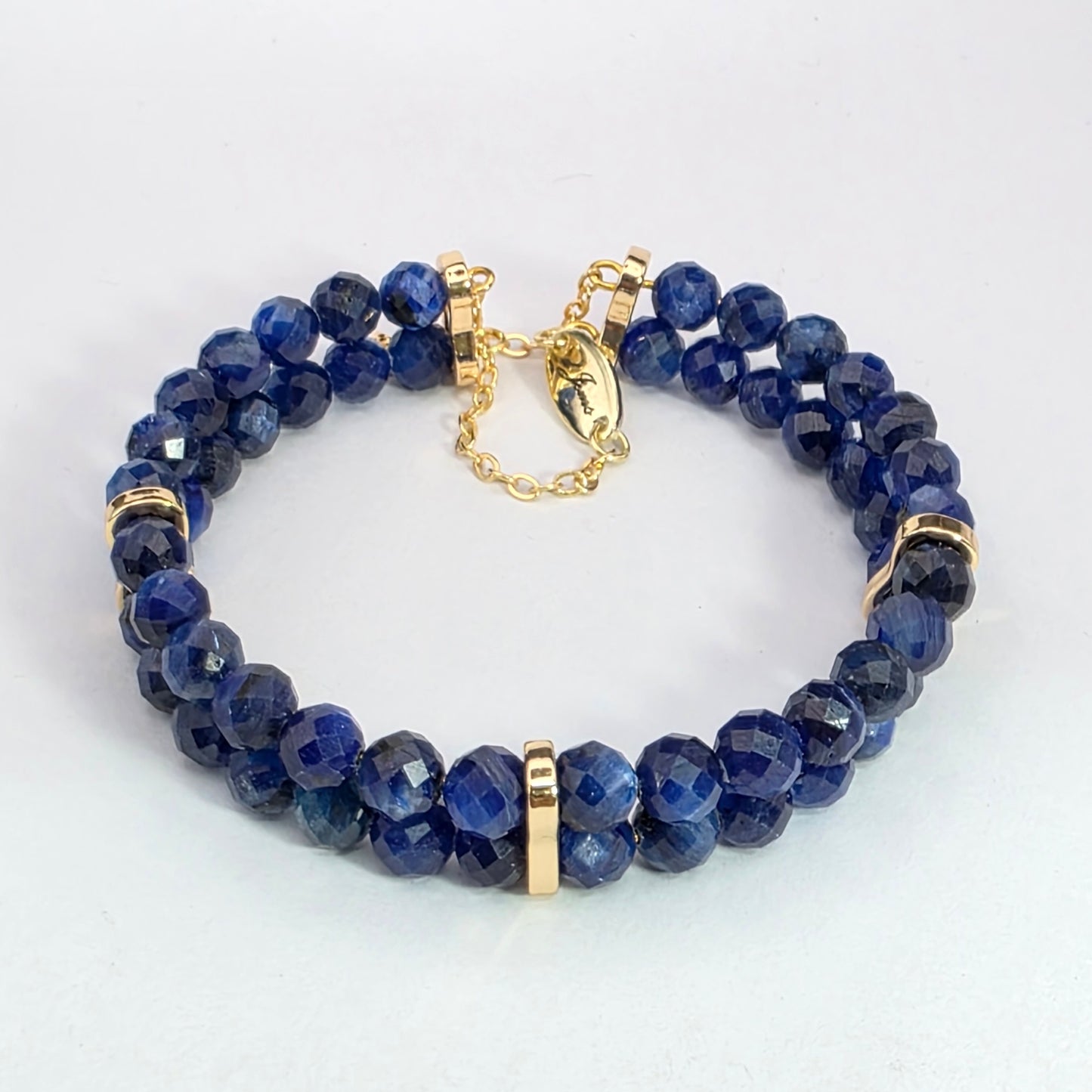 Blue beaded bracelet with gold accents on a white background