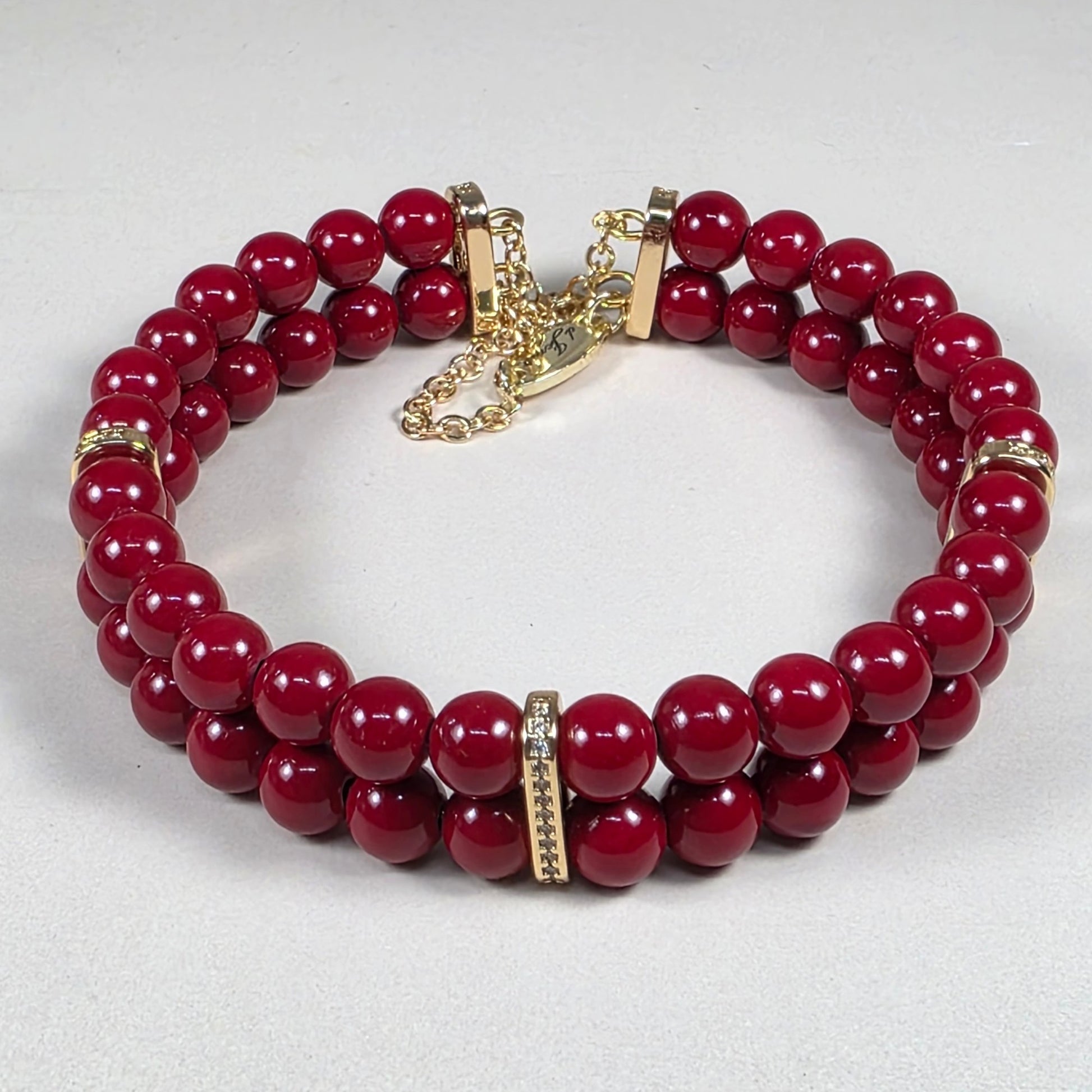 Red cinnabar bracelet with gold accents on a white background