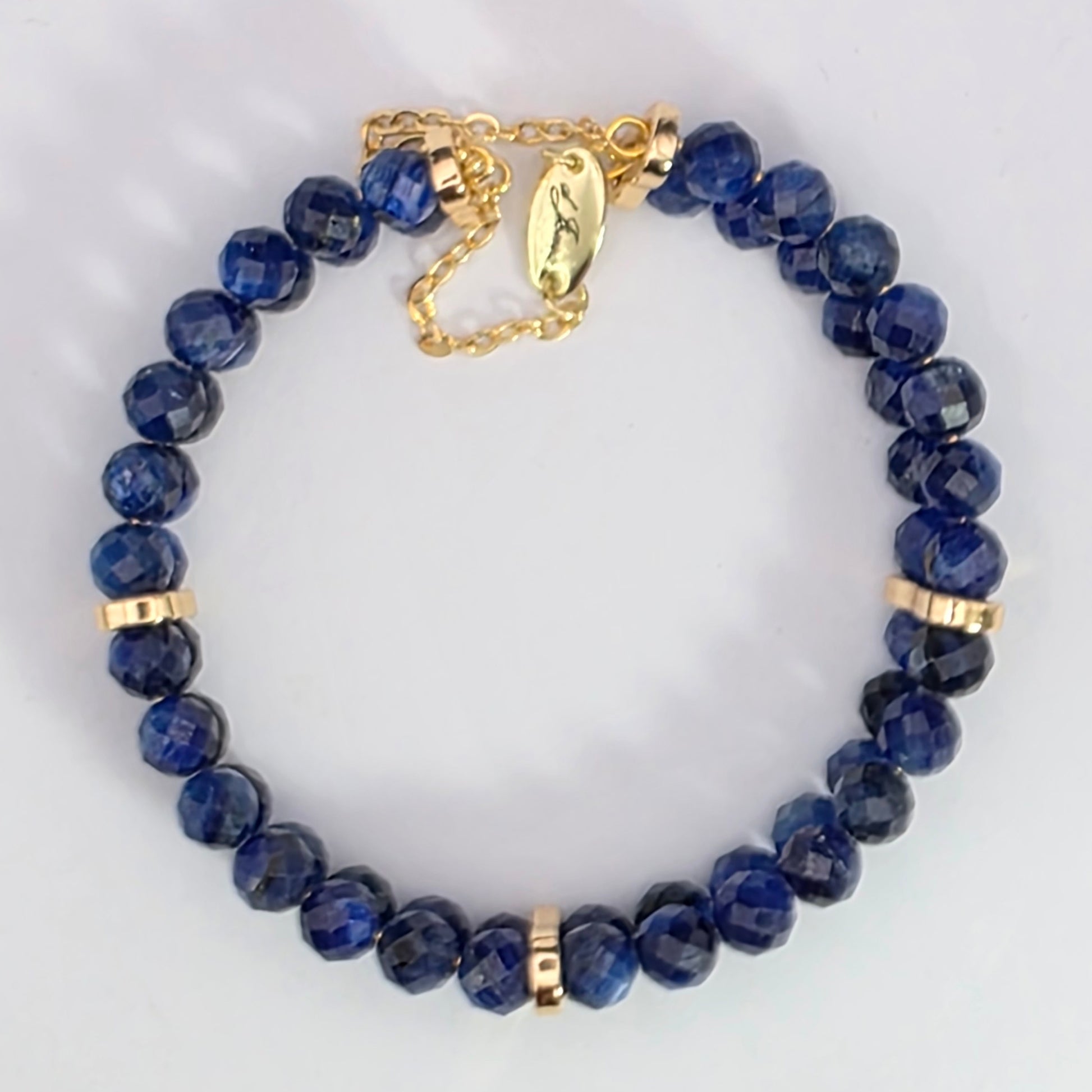 Blue beaded bracelet with gold accents on a light gray background