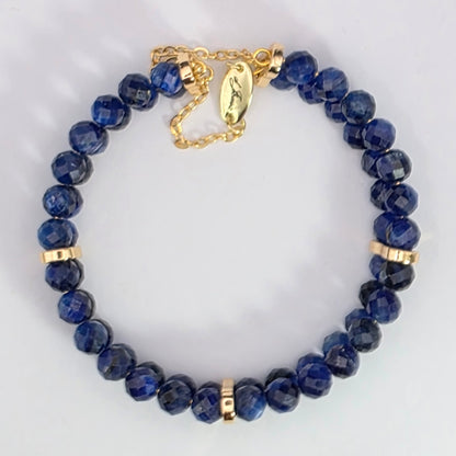 Blue beaded bracelet with gold accents on a light gray background