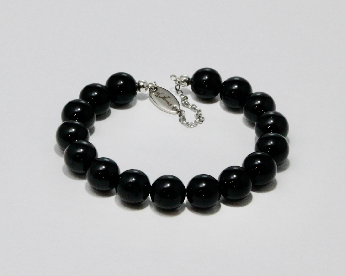 Handmade Black Tourmaline Bracelet showcasing 10mm deep black tourmaline beads on plated stainless steel memory wire with a fixed safety chain.
