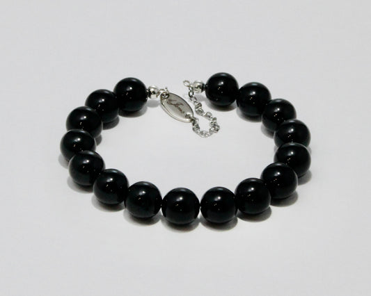 Handmade Black Tourmaline Bracelet showcasing 10mm deep black tourmaline beads on plated stainless steel memory wire with a fixed safety chain.
