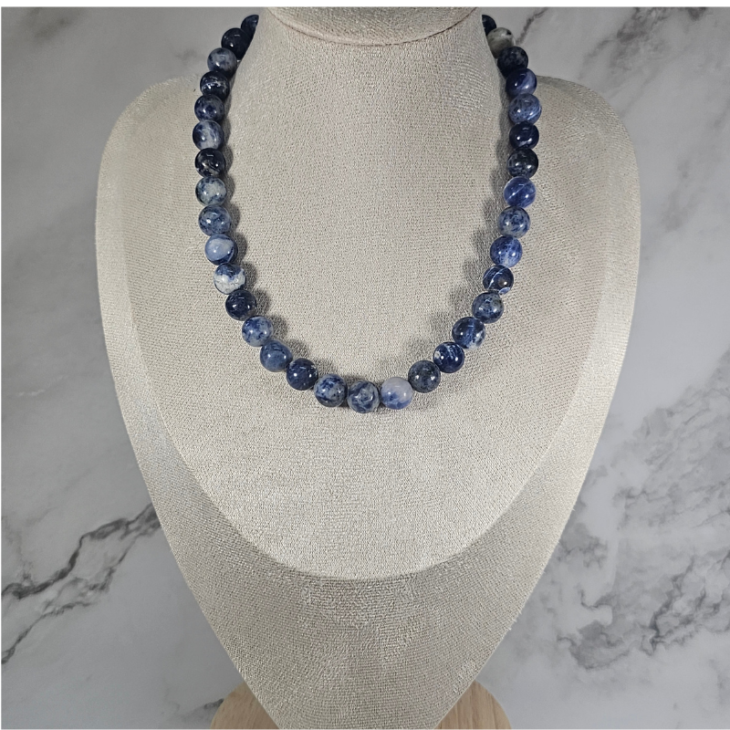 Blue beaded necklace on a mannequin bust against a marble background